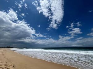 a view of the beach with a blue sky and clouds at Wollongong Tiny Home in Coniston +4 photos