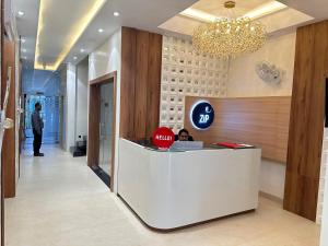 Una mujer sentada en un mostrador de recepción en un vestíbulo. en Zip By Spree Hotels R Group, en Kota