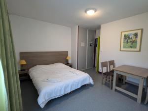 a bedroom with a bed and a table and a desk at VVF Cantal Salers Vendes in Bassignac +41 photos