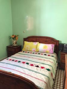 a bed with a wooden headboard and two pillows at LoveWave House in Agadir