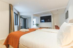 ein Schlafzimmer mit einem großen weißen Bett mit einer orangefarbenen Decke in der Unterkunft Breeze House 2 by Atlantic Holiday in Garajau