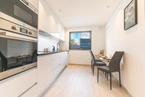 eine Küche mit weißen Schränken und einem Tisch und Stühlen in der Unterkunft Breeze House 2 by Atlantic Holiday in Garajau