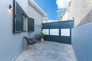 eine Terrasse mit einer schwarzen Tür und einem Stuhl in der Unterkunft Breeze House 2 by Atlantic Holiday in Garajau
