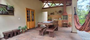 ein Esszimmer mit einem Tisch und Bänken sowie eine Küche in der Unterkunft Casa Bela, perfeita para Descanso! in Morretes