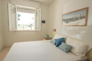 BIA'S Beach - appartamenti fronte mare في بيبيوني: غرفة نوم بسرير أبيض ونافذة