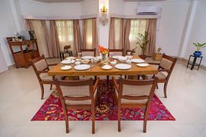 a dining room with a wooden table and chairs at amã Stays & Trails - Diffloo Bungalow, Assam in Bokākhāt +16 photos