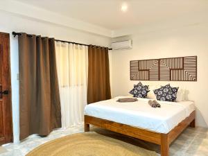 Un dormitorio con una cama con sábanas blancas y una ventana. en Villa Aniani, en El Nido