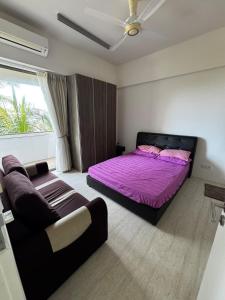 峇都丁宜Azure Haven - Seaview Resort Home, By the Sea Batu Ferringhi的一间卧室配有一张紫色的床和一张沙发