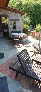 Monastero BormidaCasa Greta - Ca di Buie的一个带两张长椅、一张桌子和一座石头建筑的露台