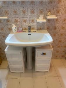 a bathroom with a white sink and some shelves at Relax House in Roccaraso