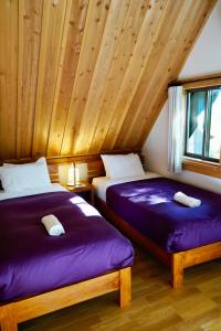 two beds in a room with a wooden ceiling at Misorano Chalet in Hakuba