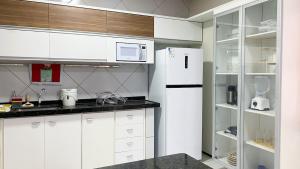a kitchen with white cabinets and a white refrigerator at CS1 - Ampla Casa com ArCond e Lazer Completo in Juazeiro do Norte