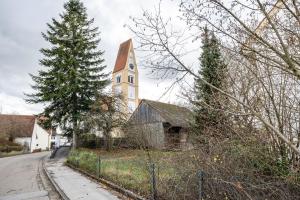 a church with a steeple on the side of a street at Leas Ferienwohnung in Aichen