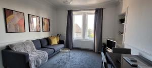 een woonkamer met een blauwe bank en een raam bij Eccles Apartment in Stirling