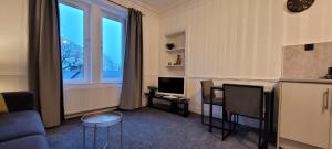 een woonkamer met een bank, een tv en een raam bij Eccles Apartment in Stirling