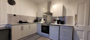 een keuken met witte kasten en een klok aan de muur bij Eccles Apartment in Stirling