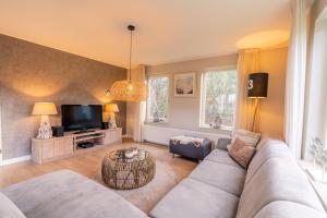 ein Wohnzimmer mit Sofa und Fernseher in der Unterkunft Villapark Kamperfoelie 73 in De Koog