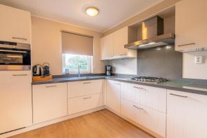 eine Küche mit weißen Schränken und einem Fenster in der Unterkunft Villapark Kamperfoelie 73 in De Koog