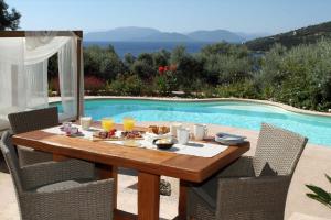 Una mesa con comida y bebidas junto a una piscina. en Villa Agapi Spacious Stone Retreat with Jacuzzi and Private Pool, en Sivota