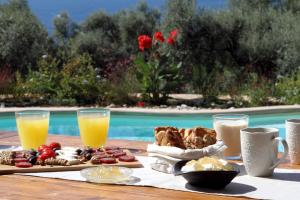 una mesa con desayuno y bebidas junto a una piscina en Villa Agapi Spacious Stone Retreat with Jacuzzi and Private Pool, en Sivota