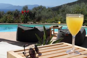 una copa de vino sentada en una mesa junto a una piscina en Villa Agapi Spacious Stone Retreat with Jacuzzi and Private Pool, en Sivota