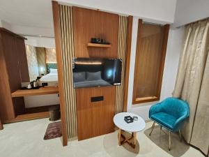 een kamer met een tv, een stoel en een wastafel bij Hotel Saffron Grand Thane in Thane