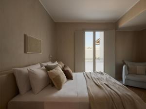 a bedroom with a large white bed with a chair at Akria Seaside Suites in Naousa