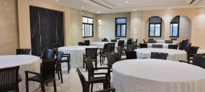 a room with white tables and chairs and windows at Abhushan Mahal in Nīmri