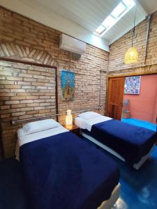 瓜拉雷马Charmosa casa na Estação Ferroviária de Luís Carlos的一间卧室，有两张床和一堵砖墙