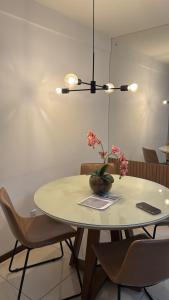 une table de salle à manger avec un vase de fleurs dessus dans l'établissement Apartamento próximo a praia, à Maceió