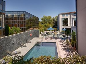 une piscine avec des chaises et des tables sur un bâtiment dans l'établissement Radisson Hotel Aix En Provence, à Aix-en-Provence
