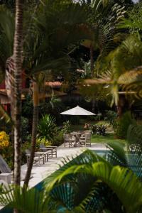 eine Terrasse mit Tischen und Stühlen und einem Sonnenschirm in der Unterkunft Machê Pousada & Boutique - A mais charmosa de Arraial D ajuda in Arraial d'Ajuda