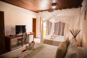 ein Schlafzimmer mit einem Bett, einem Schreibtisch und einem Fernseher in der Unterkunft Machê Pousada & Boutique - A mais charmosa de Arraial D ajuda in Arraial d'Ajuda + 43 Fotos