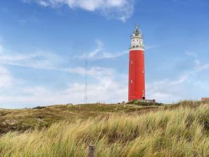 a red and white lighthouse on top of a hill at Serene Holiday Home in De Koog Texel with Sauna in Westermient