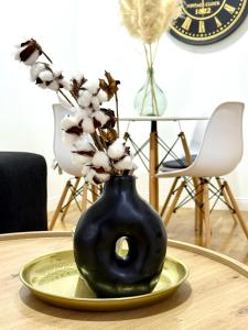 un jarrón negro con flores en una mesa en Apartman Mir, en Temerin