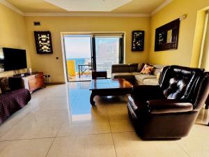 a living room with a couch and a table at Seaview Family Apartment, Pool, Easy Access to the Sea, Near Mellieħa Bay in Mellieħa