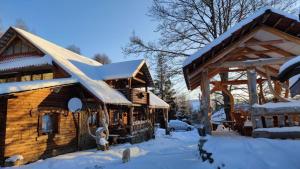 una cabaña de troncos con nieve en el techo en Під Горбком, en Bukovets