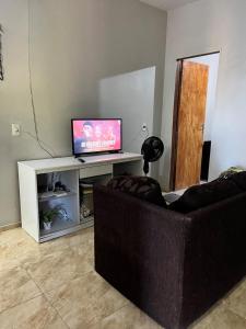 a living room with a couch and a flat screen tv at Chalé Canto dos Pássaros in Viçosa do Ceará