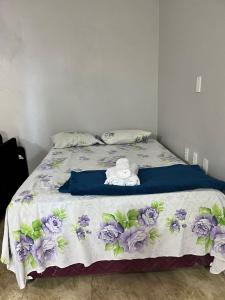 a bedroom with a bed with purple flowers on it at Chalé Canto dos Pássaros in Viçosa do Ceará