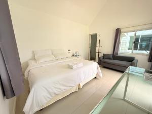 ein weißes Schlafzimmer mit einem Bett und einem Stuhl in der Unterkunft Pophouse in Phetchaburi