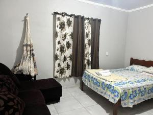 a bedroom with a bed and a chair and a couch at Chalé Canto dos Pássaros in Viçosa do Ceará +22 photos