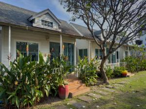 ein weißes Haus mit einer Veranda und einigen Pflanzen in der Unterkunft Pophouse in Phetchaburi