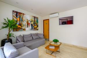 a living room with a couch and a painting on the wall at OYO Tropical Confort Hotel, Brasilia in Brasília