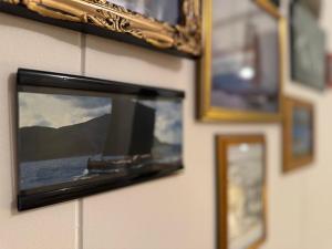 a television hanging on a wall with pictures at Lofoten Light in Vestvågøya