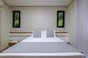 a bedroom with a white bed and two pictures on the wall at OYO Tropical Confort Hotel, Brasilia in Brasília