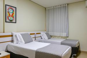 a hotel room with two beds and a window at OYO Tropical Confort Hotel, Brasilia in Brasília