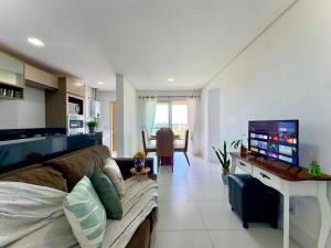 a living room with a couch and a flat screen tv at Apartamento em condomínio HOME CLUB, cozinha completa, PISCINA e JACUZZI aquecida, SAUNA, ACADEMIA, quadra de esportes playground infantil, salão de jogos a 40m da PRAIA e 15min do Beto Carreiro in Piçarras