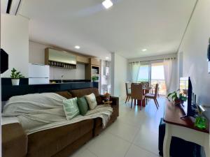 a living room with a couch and a kitchen at Apartamento em condomínio HOME CLUB, cozinha completa, PISCINA e JACUZZI aquecida, SAUNA, ACADEMIA, quadra de esportes playground infantil, salão de jogos a 40m da PRAIA e 15min do Beto Carreiro in Piçarras +17 photos