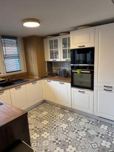 eine Küche mit weißen Schränken und einem Fliesenboden in der Unterkunft Loft Opale in Calais