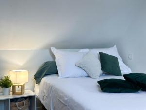 Una cama con almohadas verdes y blancas. en Le P'tit Cocoon, en Lorient
